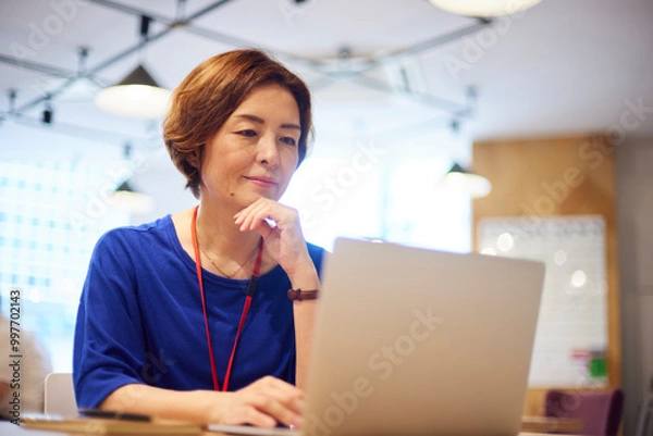 Fototapeta オフィスにてノートパソコンで仕事をする日本人ビジネスウーマン