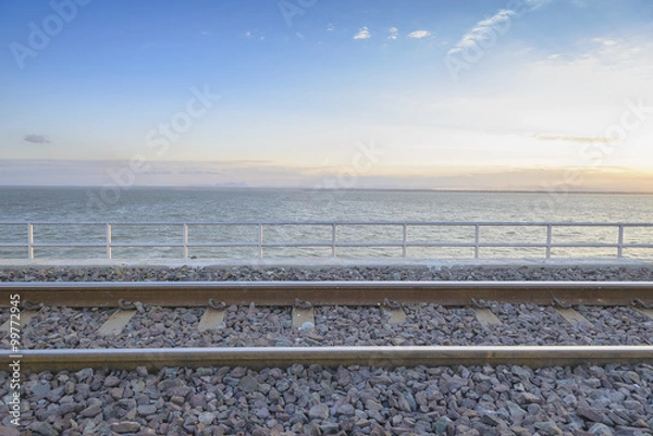 Fototapeta railway or railroad crossing to the lake with the morning light