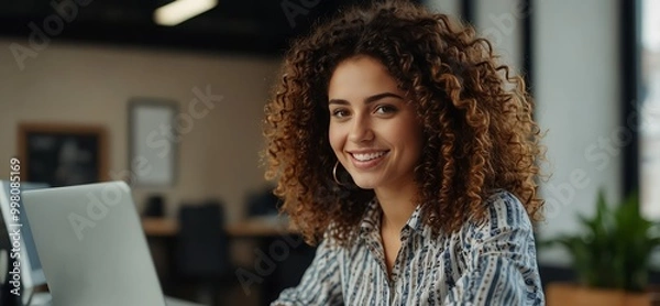 Obraz Portrait of a Happy Middle Eastern Manager Sitting at a Desk in Creative Office. Young Stylish Female with Curly Hair Using Laptop Computer in Marketing Agency