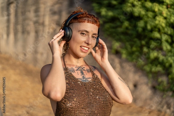 Obraz Smiling informal woman listening to music during summer
