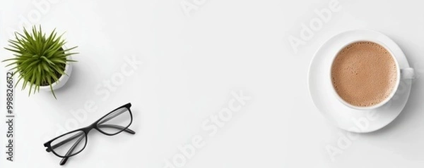 Fototapeta Coffee cup, glasses, and potted plant on a clean white background for a cozy workspace atmosphere.