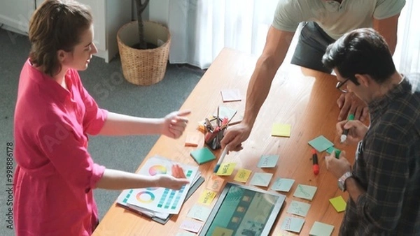 Fototapeta Top view of manager writing idea on sticky notes and explain idea about web design. Professional marketing team or programmer brainstorming idea while looking at tablet with color palette. Symposium.