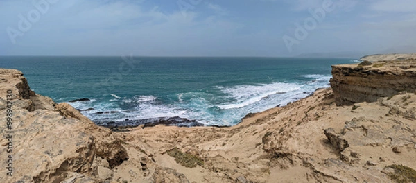 Fototapeta Panoramic view of the sandy slopes and cliffs of the rocky west coast of the island of Furteventura in the Canary Islands under a blue cloudy sky