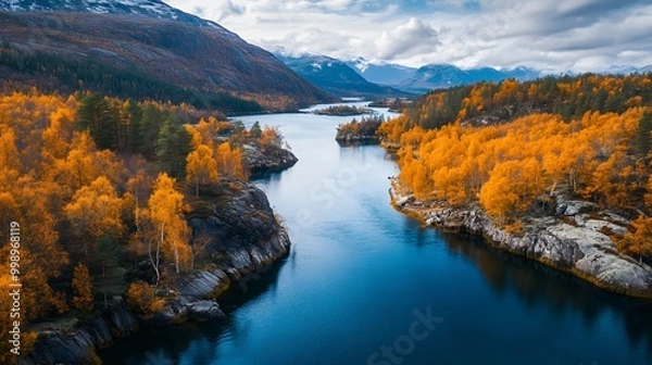 Fototapeta The deep blue water of the lake is surrounded by high cliffs and orange trees, with autumn colors