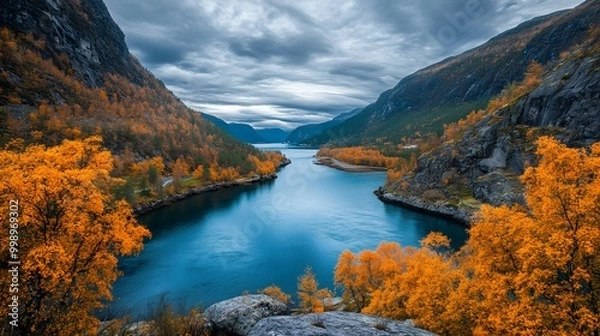 Fototapeta The deep blue water of the lake is surrounded by high cliffs and orange trees, with autumn colors