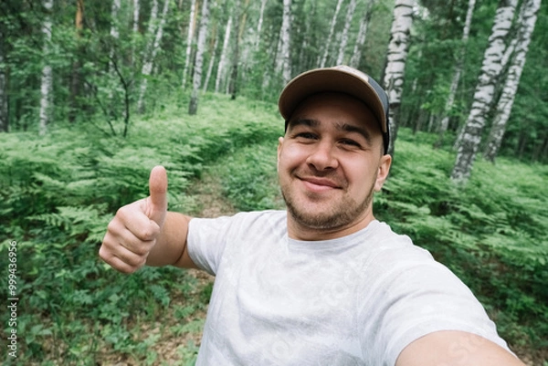 Fototapeta Man smiling and taking a selfie in the forest
