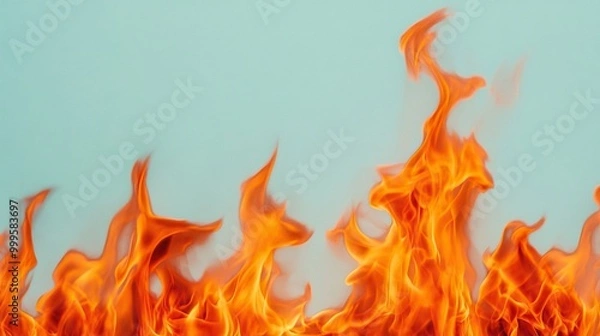 Fototapeta Flames dancing against a soft blue background, creating a striking visual contrast.