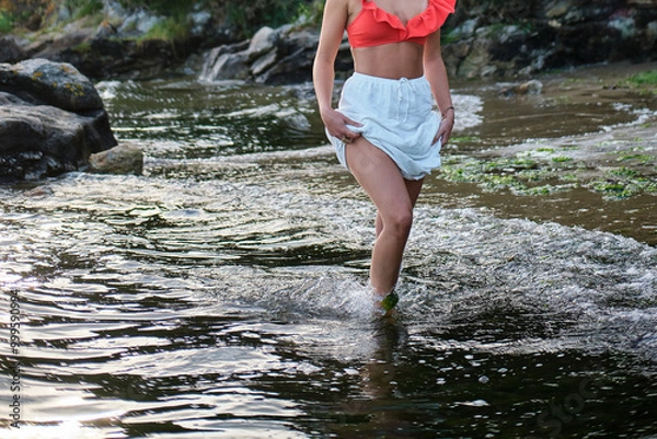 Fototapeta Mujer joven y en forma caminando por una playa salvaje durante el atardecer. 