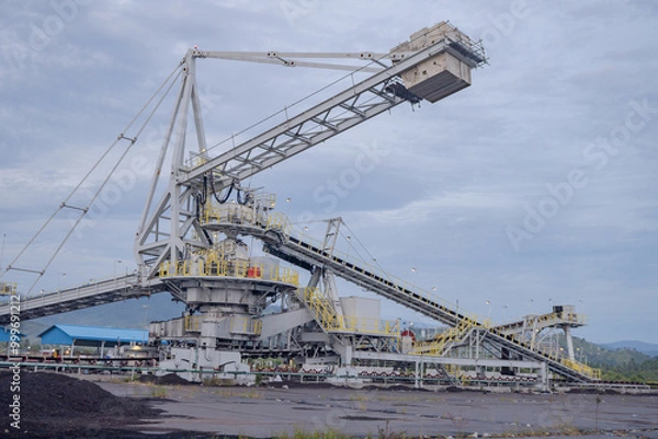 Obraz Industrial Conveyor Belt System. A large industrial conveyor belt system with a crane in a mining facility.