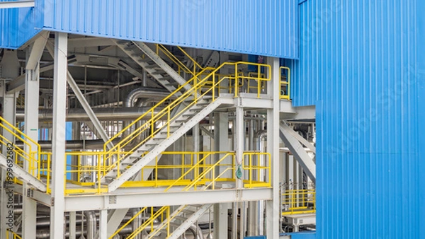 Obraz Industrial Structure with Stairs and Pipes.  An industrial structure featuring a set of stairs and pipes, highlighting the intricate details of industrial design and construction.