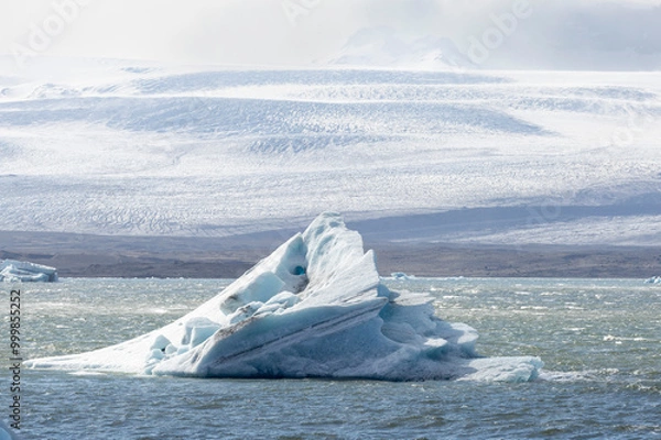 Fototapeta a single iceberg is floating  in the wavy glacial lagoon and glacier, Iceland