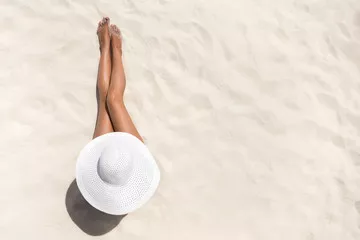 Fototapeta Koncepcja mody wakacje lato - opalająca się kobieta w kapeluszu na plaży na białym piasku strzał z góry