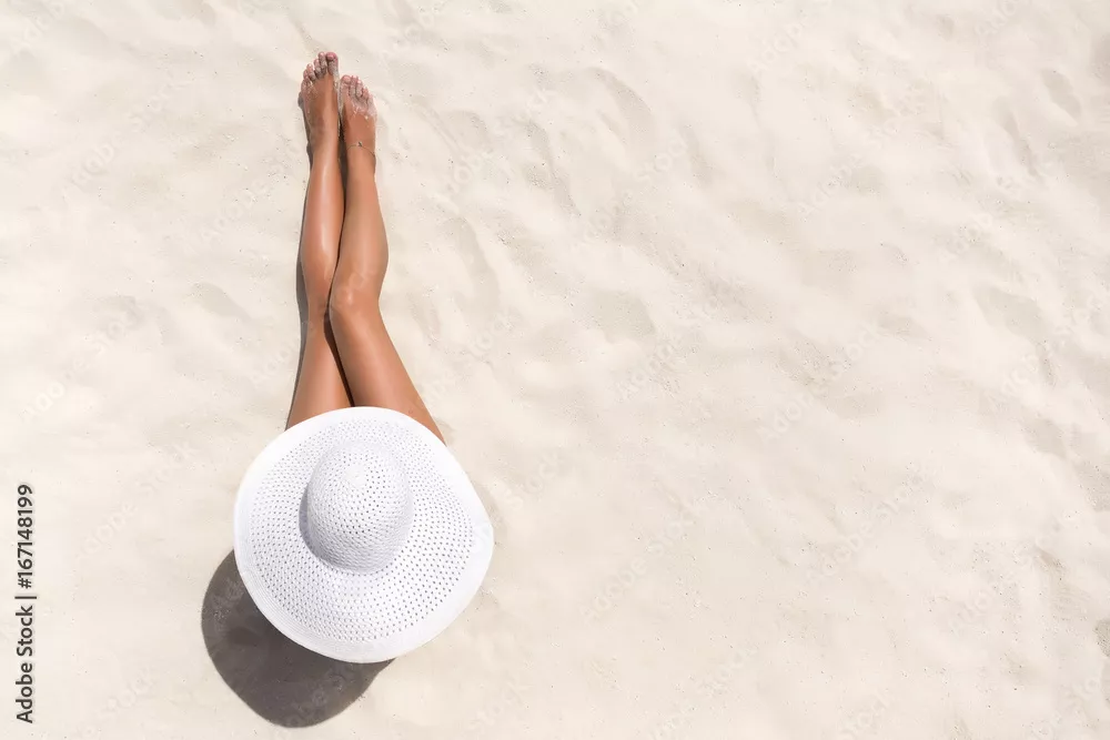 Fototapeta Koncepcja mody wakacje lato - opalająca się kobieta w kapeluszu na plaży na białym piasku strzał z góry