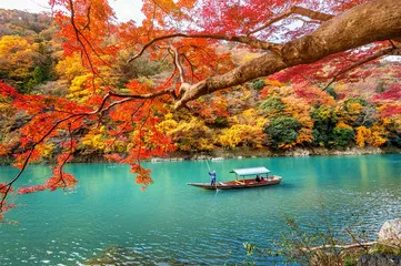 Fototapeta Boatman pływa łodzią po rzece. Arashiyama jesienią wzdłuż rzeki w Kioto w Japonii.