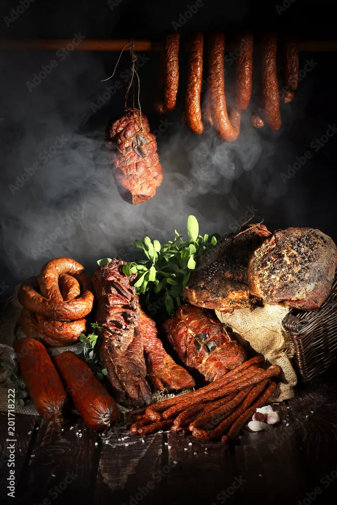 Fototapeta Smakowite wędliny. Tradycyjnie wędzone wędliny w kompozycji na lnianym obrusie z ziołami