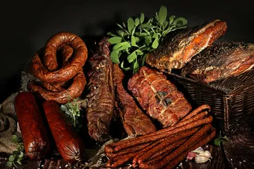 Fototapeta Wędzone wędliny, tradycyjny smak. Tradycyjnie wędzone wędliny w kompozycji na lnianym obrusie z ziołami