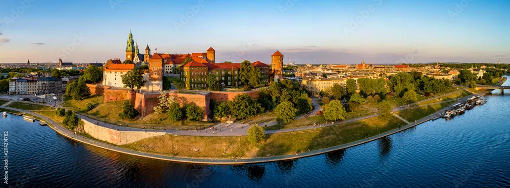 Fototapeta Kraków, Polska. Szeroka panorama z lotu ptaka o zachodzie słońca z Zamkiem Królewskim na Wawelu i katedrą. Daleki widok na stare miasto i dawną żydowską dzielnicę Kazimierz. Wisła, park, promenada i spacerowicze