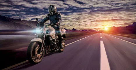 Fototapeta motocyklista jedzie wieczorem do domu autostradą o zachodzie słońca