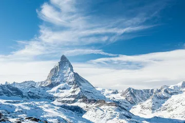 Fototapeta Malowniczy widok na ośnieżony szczyt Matterhorn w słoneczny dzień z błękitnym niebem i dramatycznymi chmurami w tle, Szwajcaria.