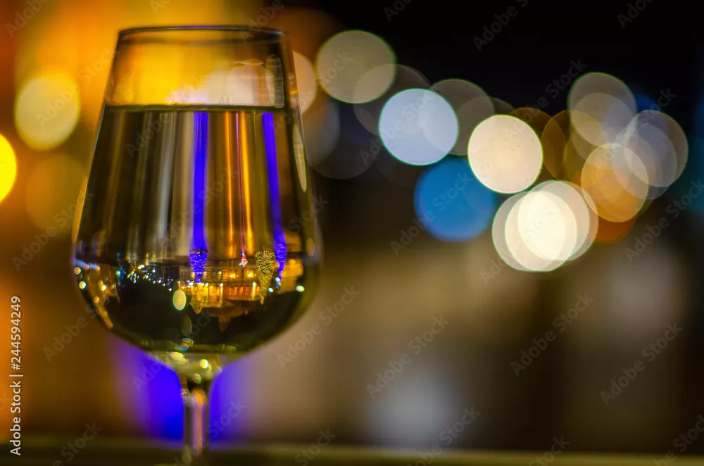Fototapeta Kieliszek do wina białego z odbiciem światła, niewyraźne tło bokeh. Uroczystość.