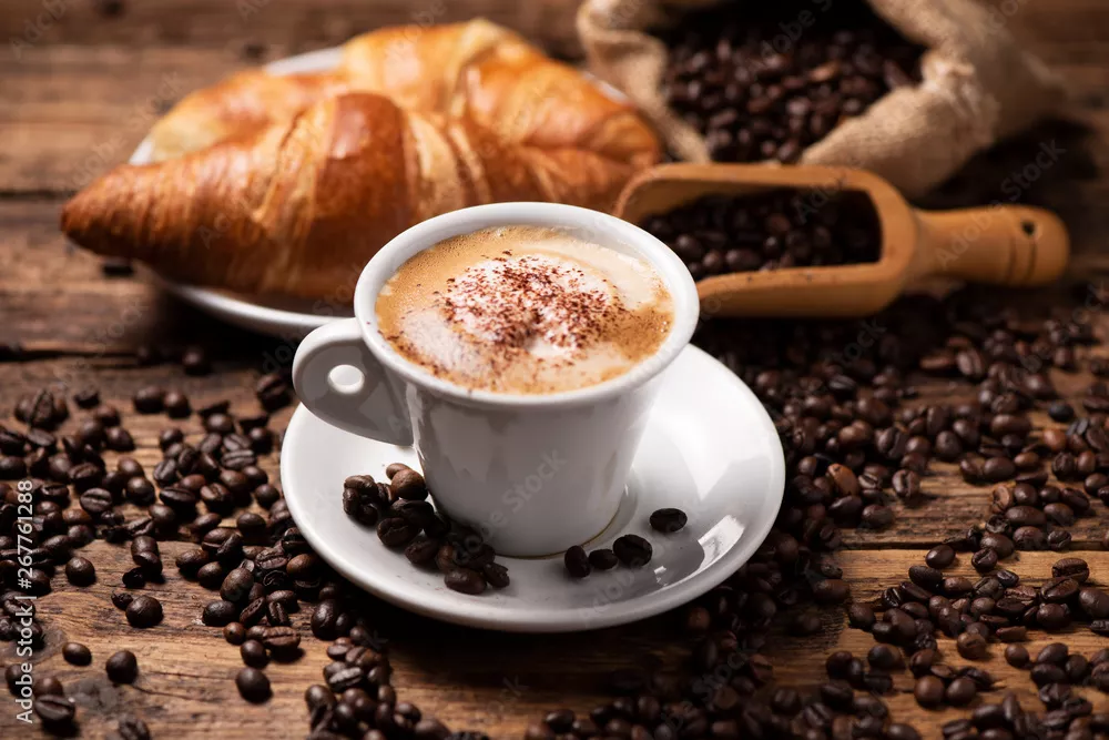 Fototapeta Filiżanka cappuccino z ziaren kawy jako tło.