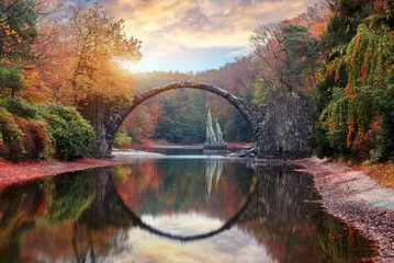 Fototapeta Fantastyczny jesienny krajobraz. Niesamowity zachód słońca Z kolorowym niebem w azalii i parku rododendronów Kromlau. Most Rakotz, Most diabła Rakotzbrücke w Kromlau, Saksonia, Niemcy.