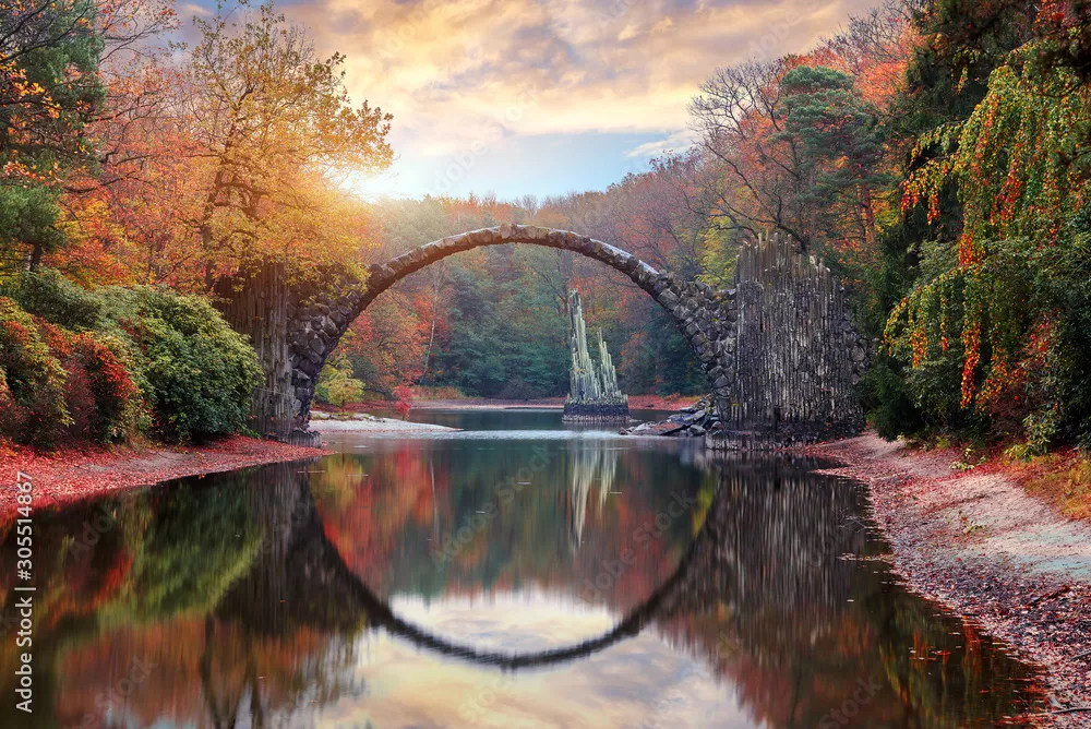 Fototapeta Fantastyczny jesienny krajobraz. Niesamowity zachód słońca Z kolorowym niebem w azalii i parku rododendronów Kromlau. Most Rakotz, Most diabła Rakotzbrücke w Kromlau, Saksonia, Niemcy.