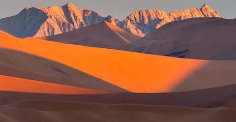 Fototapeta Wydmy i góry Naukluft w złotym blasku zachodu słońca w parku Namib-Naukluft; Sossusvlei, Namibia