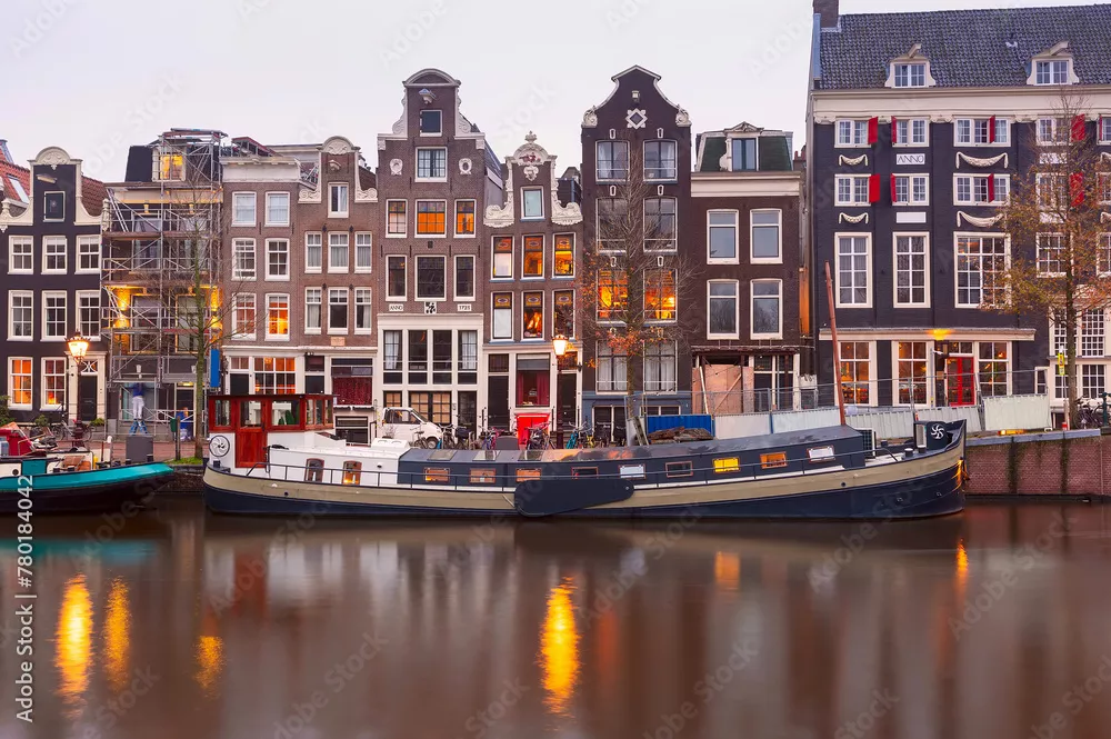 Fototapeta Amsterdamski kanał Singel z typowymi holenderskimi domami podczas porannej niebieskiej godziny, Holandia, Holandia.