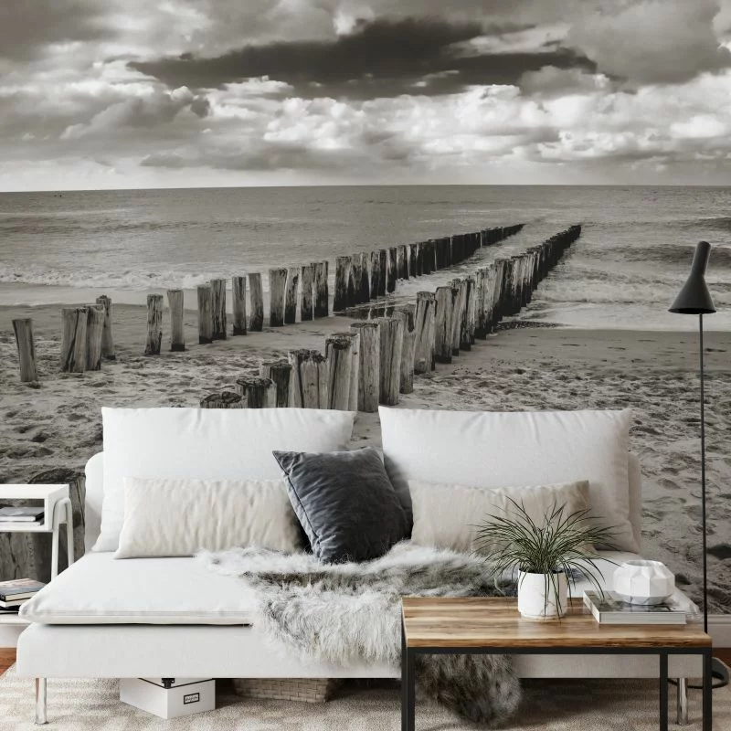Fototapeta - Drewniane Falochrony na Plaży w Odcieniach Szarości - obrazek 1